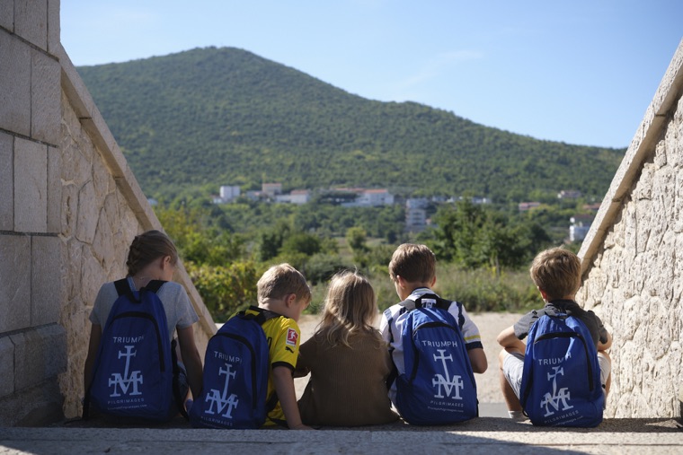 Young pilgrims with Triumph backpacks looking out toward the mountain