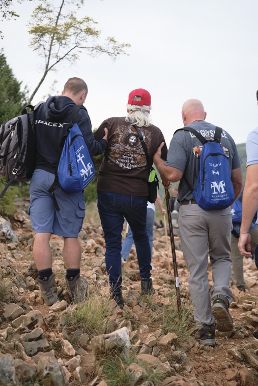 Three pilgrims with Triumph backpacks climbing the hill