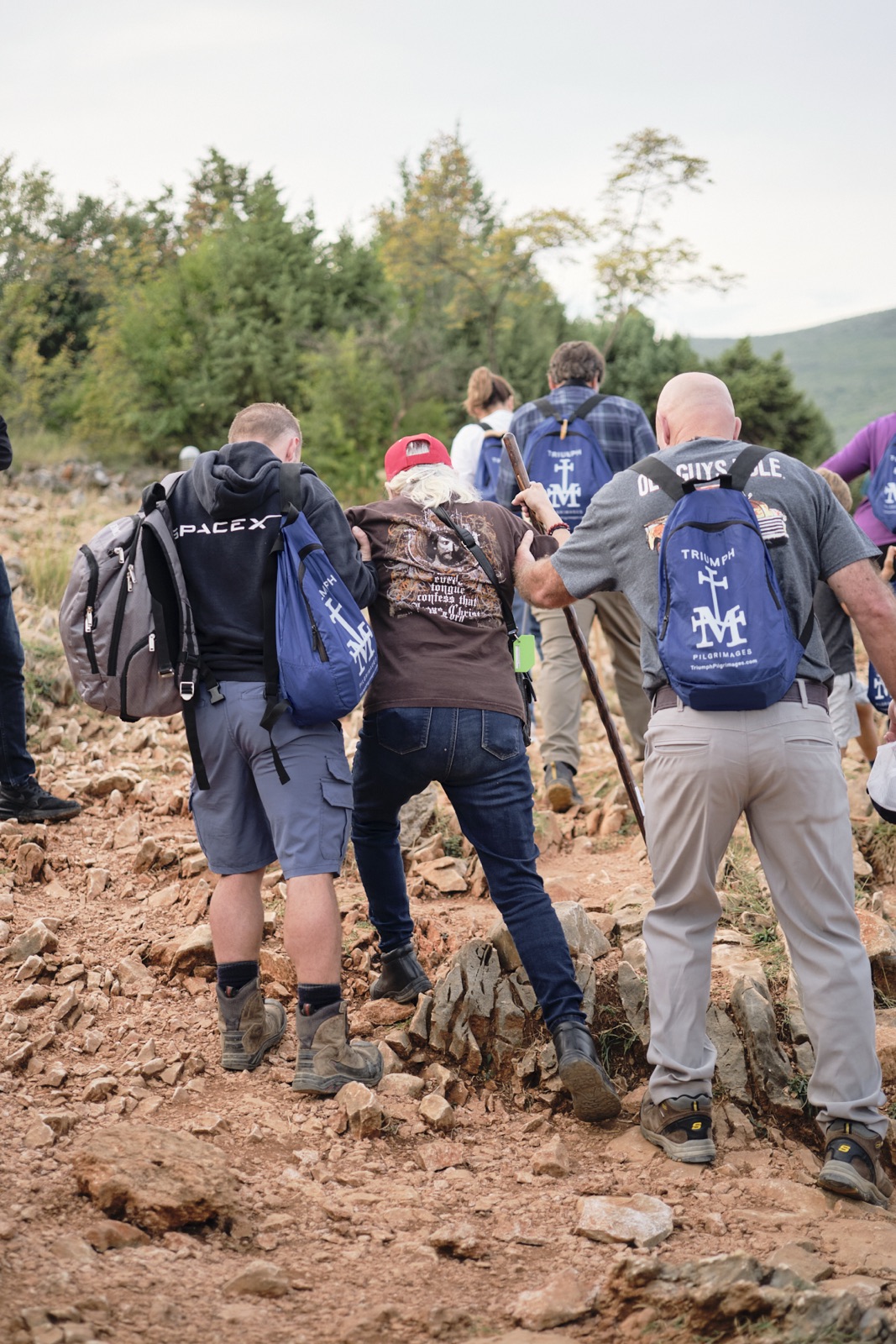 Pilgrims helping one another up the rocky path