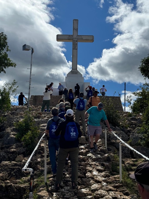 Pilgrims climbing the steps to the white cross on Cross Mountain
