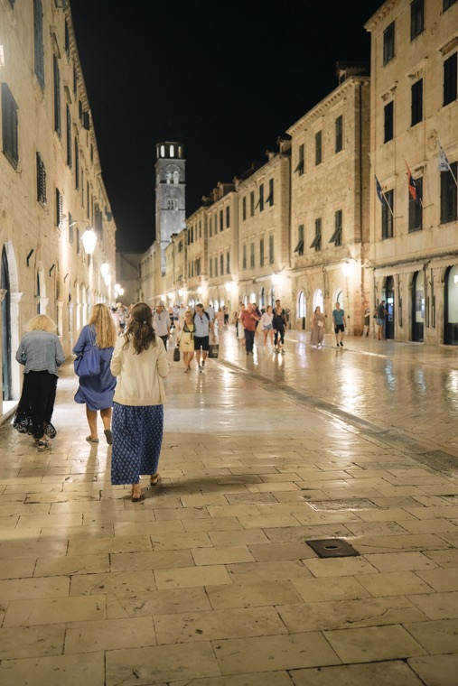 Pilgrims walking the lit stone street of the old town
