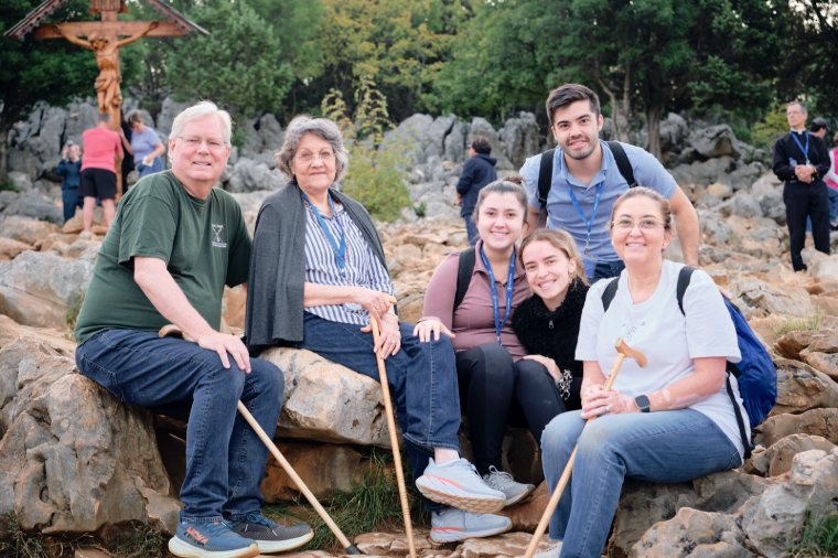 Pilgrims resting together among the rocks below a crucifix