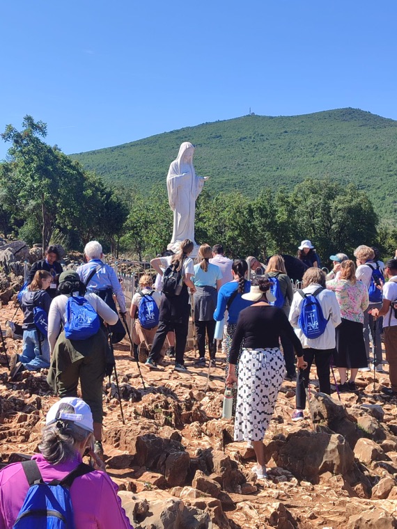 Pilgrims with Triumph backpacks climbing toward the statue