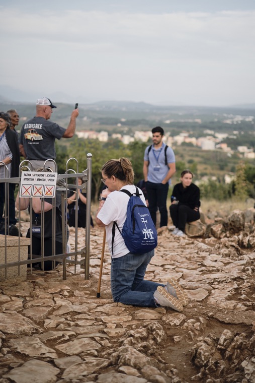 A pilgrim kneeling in prayer on the rocky hilltop