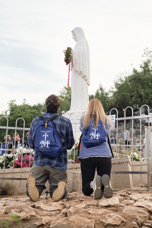Two pilgrims kneeling before the statue of Our Lady