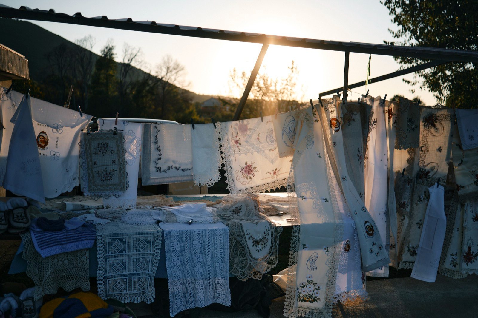 Embroidered lace hanging at a village stall at sunset