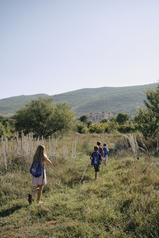 Pilgrims walking through a meadow toward the hills
