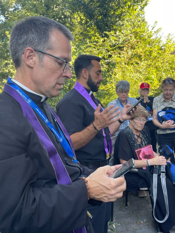 Two priests in purple stoles leading prayer outdoors