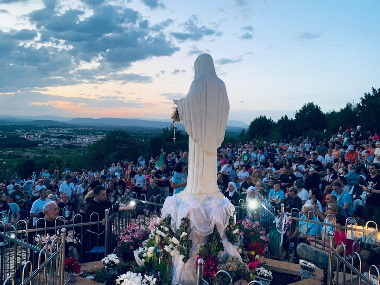 An evening crowd gathered before the statue on Apparition Hill