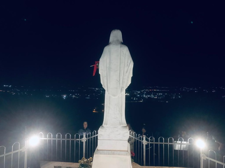 The statue of Our Lady lit at night above the village