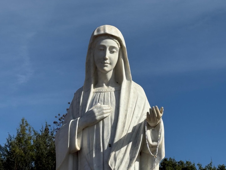 The statue of Our Lady against a deep blue sky