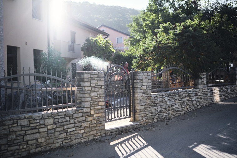 A stone wall and gate in the village, in the morning sun